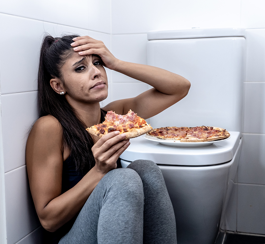 Image of a girl eating pizza next to a toilet