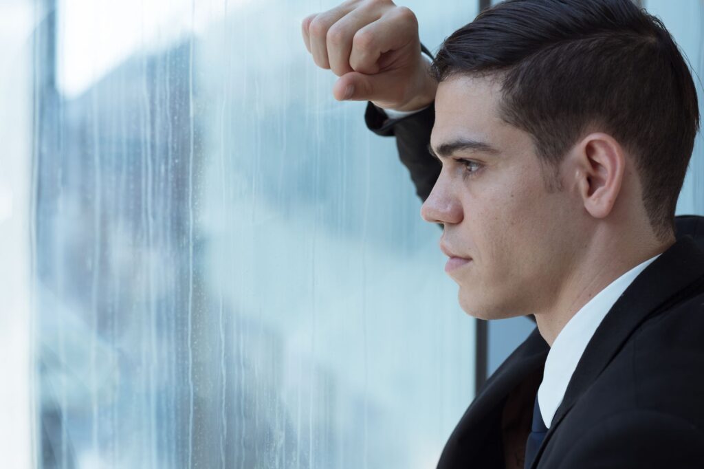 man stares out of his office window in los angeles; suffering from an attachment disorder.